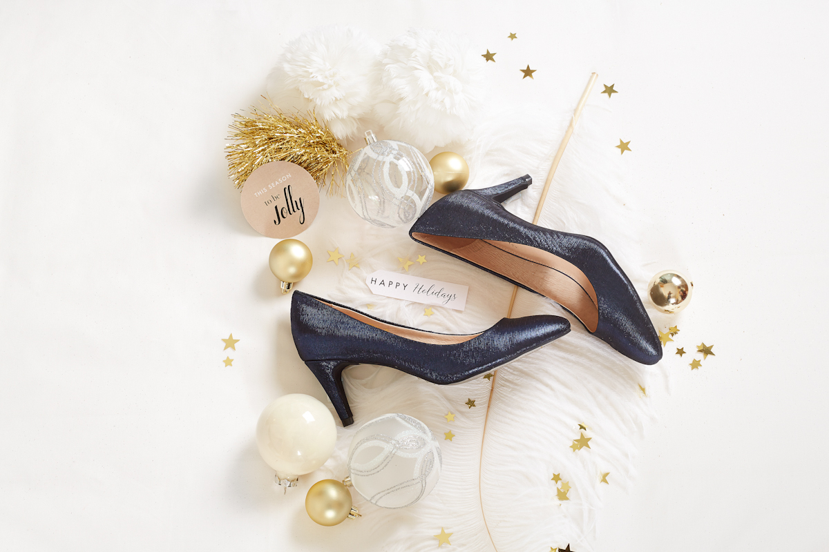 Flatlay product photography - a pair of shiny navy blue heels surrounded by Christmas ornaments - Mount Studio